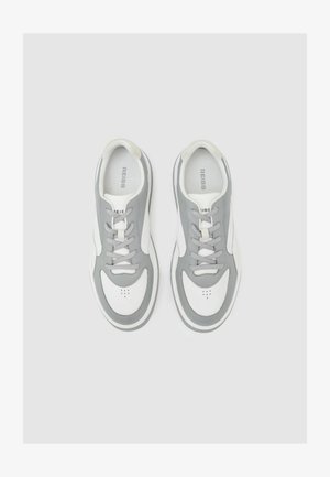 Grå og hvide atletiksneakers med en glat læderoverdel, polstret krave, rund tå og snørelukning. Diskrete perforeringsdetaljer.