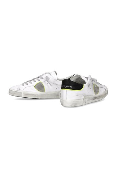 Zapatillas de cuero blancas con acentos en gris y amarillo neón, panel lateral texturizado y suela de goma que muestra un ligero desgaste. Diseño clásico de cordones.