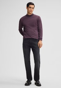 Dunkelviolett, langärmliger Rollkragenpullover, kombiniert mit dunklen Jeans und schwarzen Schnürschuhen. Einfaches Design, glatte Textur und taillierte Form.
