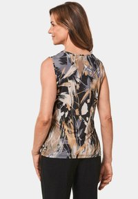 Mouwloze top met een abstract patroon in beige, zwart en grijstinten; aansluitend ontwerp met zachte, gemêleerde stof.