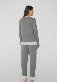 Conjunto de camiseta de manga larga y pantalones en gris, presenta un delicado encaje blanco en el dobladillo. Fabricado en un tejido suave con un corte holgado, ideal para ropa de estar por casa.