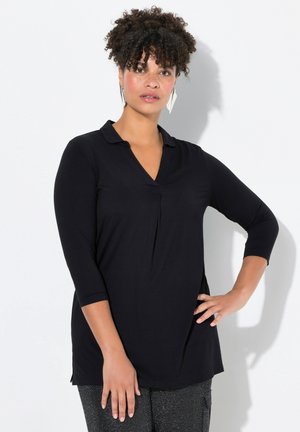 Chemise noire à manches longues avec col, décolleté en V et détails plissés. Texture lisse, fentes sur les côtés, associée à un pantalon noir texturé.