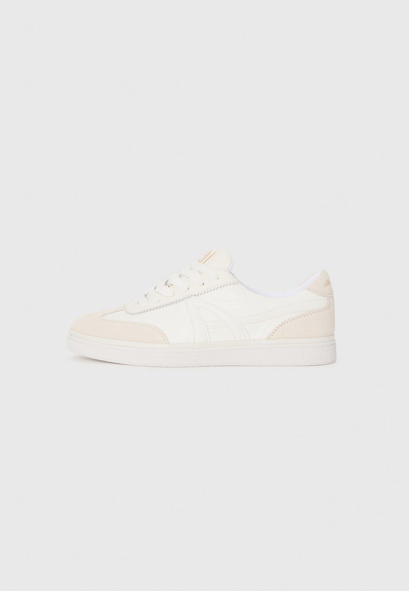 Zapatillas blancas con acentos de ante beige, parte superior texturizada, puntera redonda, suela plana y cordones prominentes. Diseño minimalista con detalle de logotipo.