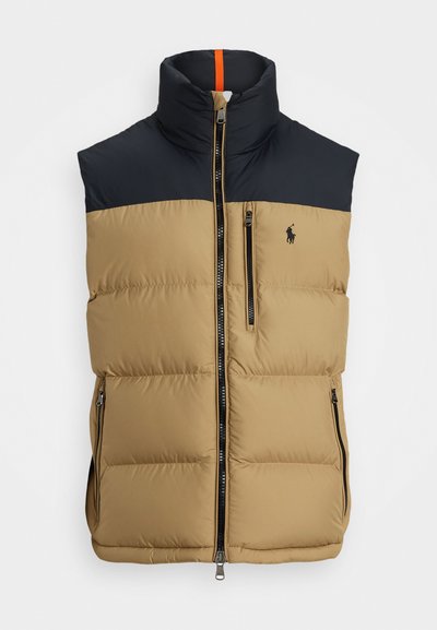 Beige og marineblå puffervest med høj krave, featuring en frontlynlås, sidelommer og et logo på brystet. Orange accent ved halsen.