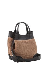 Sacoche en shearling brun et cuir noir avec des poignées doubles, une sangle amovible et des accents en métal doré. Le tissu texturé contraste avec le cuir lisse.