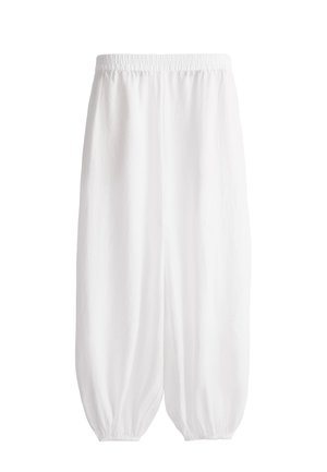 Pantalon blanc ample avec taille élastique et poignets élastiques froncés aux chevilles, présenté sur un fond uni.
