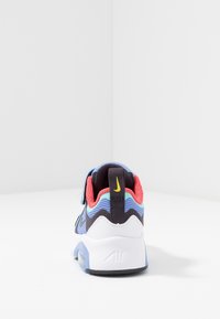 Flerfärgad träningssko med meshtyg i blått, svart och rött, vit sula, justerbar rem och hällapp med logotyp.