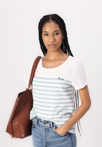 Vit kortärmad t-shirt med ljusblå horisontella ränder och "love" broderat i marinblått. I kombination med blå högmidjade jeans och en brun väska.