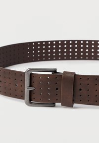 Rudas perforuotas odinis diržas su šlifuotos metalinės sagties, turintis lygų paviršių ir tolygiai išdėstytas skylutes pritaikymui.