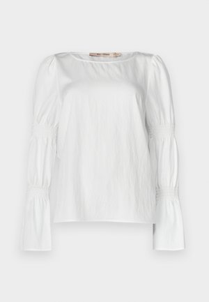 Fehér, hosszú ujjú blúz könnyű anyagból, kerek nyakkivágással és ráncolt, gumis bokrétás ujjakkal, smock részlettel.
