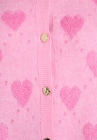 Roosa kootud kangas tekstuursete südame mustritega ja läikivate ebaühtlaste ümmarguste nuppudega, mis asetsevad ribitud nööpplokil.