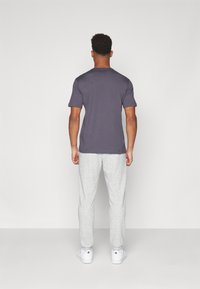 Tricou gri cu mânecă scurtă și pantaloni de trening gri deschis. Tricoul are o croială lejeră, iar pantalonii au un picior conic și manșete elastice.
