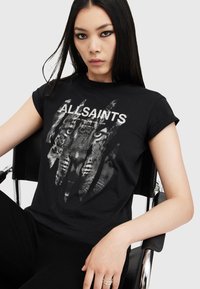 Camiseta negra con un diseño gráfico de caras de tigre con efectos desgastados y el texto "ALLSAINTS" en letras blancas en negrita. Mangas cortas.