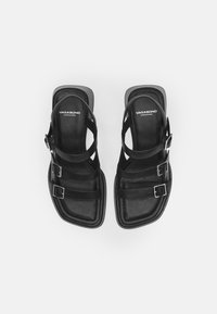 Black leather sandals with three adjustable straps and silver buckles. Square toe and flat sole. Brand name "VAGABOND" on insoles.
