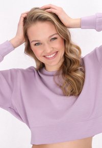 Lichtpaarse cropped sweatshirt met een ronde hals en brede mouwen. Soepele textuur en subtiele stiksels langs de zoom.