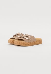 Light brown slip-on sandals with a suede upper, knotted metallic accent, and a textured cork platform sole. Open-toe design.