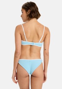 Light blue bikini set featuring a textured fabric and thin adjustable straps. The top has a clasp closure at the back, and the bottoms are low-rise.
