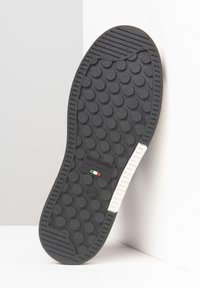Suola di scarpa in gomma nera con motivi di presa rotondi, accenti bianchi e un'etichetta che recita "Nero Giardini, Made in Italy." Misura 37.