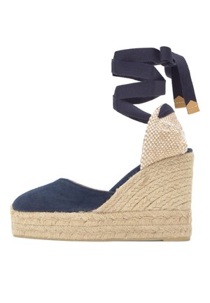 Cuña de esparto azul marino con plataforma de yute trenzado y tiras para atar en el tobillo, con detalle de tacón a cuadros en beige.