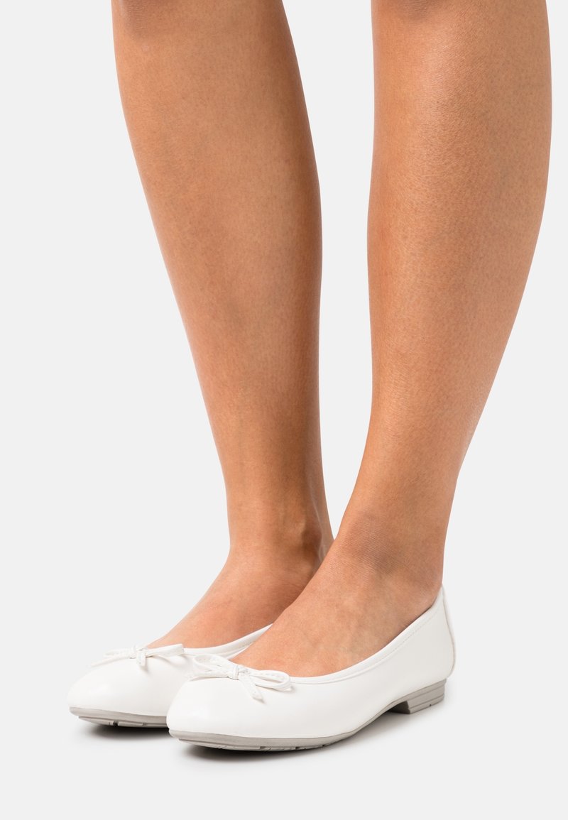 Ballerines blanches en cuir lisse, présentant un bout arrondi, un petit nœud décoratif à l'avant, et une semelle basse et flexible.