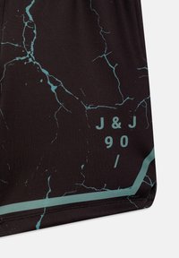 Shorts noirs avec un motif turquoise craquelé et un texte en relief "J&J 90 /" le long de l'ourlet. Confectionnés dans un tissu lisse et extensible.