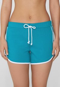 Pantaloni corti in cotone teal con accenti bianchi, dotati di vita con cordino, orli curvi e una texture liscia. Nessuna tasca visibile.
