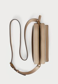 Geantă crossbody din piele bej cu o formă structurată, prezentând un închizător superior cu fermoar, curea ajustabilă și accente de hardware aurii.