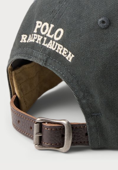 Căciulă din bumbac verde închis, brodată cu "POLO RALPH LAUREN." Dispune de o curea din piele maro cu o cataramă argintie și o căptușeală bej quilted în interior.