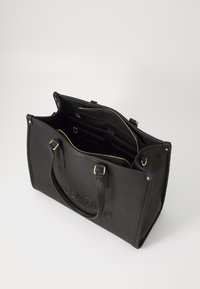 Black tote bag in textured material with gold-tone hardware, featuring a spacious interior and a zippered closure. "VALENTINO" embossed on front.