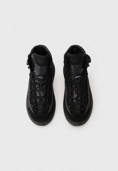 Un paio di sneakers alte nere con colli imbottiti, lacci elastici e branding "M8" sulla linguetta, viste dall'alto su uno sfondo bianco.