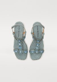 Sandales en daim bleu avec des embellissements décoratifs en perles de verre. Design à lanières avec une semelle plate et une boucle de cheville réglable.