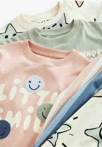 Fire sweatshirts stablet: en pink med en smiley applikation, en lys grøn med tekstur skrift, en creme med grafik og en blå stribet stof.