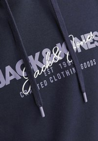 Sudadera azul marino de algodón con cordones y un logo impreso. Presenta una mezcla de tipografía en negrita y cursiva en gris claro y blanco.