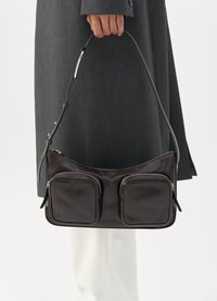 Brown leather shoulder bag with dual front pockets, silver zippers, and an adjustable strap, set against a neutral background.