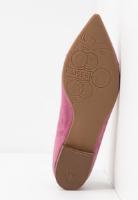Chaussure en daim rose à bout pointu, dotée d'une semelle en caoutchouc marron embossée de pièces de monnaie et de détails de marque de Peter Kaiser.