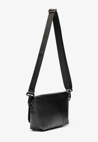 Borsa a tracolla nera in pelle con un design testurizzato, dotata di una larga tracolla regolabile e dettagli di cucitura sottili sul davanti.