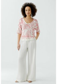 Witte wijde broek gecombineerd met een kortmouwige, roze top met een bloemenpatroon, een V-hals en een onderband met tekst.