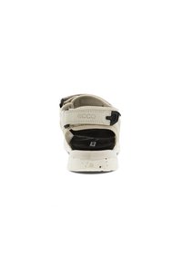 Ecco sandaler med en ljusbeige ovandel med en texturerad yta, justerbar rem och en svart fotbädd på en vitprickig sula.