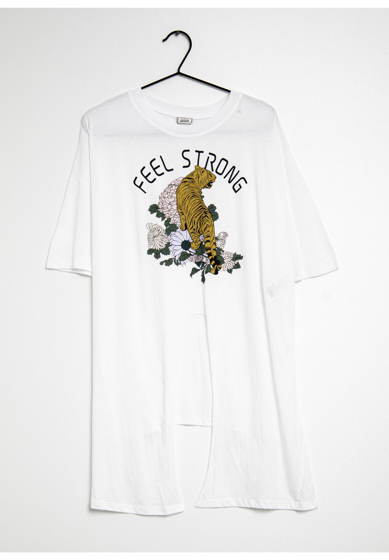 T-shirt bianco oversize con una grafica di una tigre gialla e fiori con il testo "FEEL STRONG" in nero. Maniche corte e tessuto leggero.