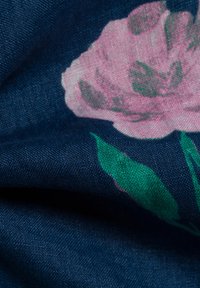 Stof met bloemenpatroon, met een donkere marineblauwe achtergrond, een grote roze bloem en groene bladeren, die een gestructureerde, geweven uitstraling heeft.