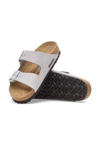Birkenstock-sandalen met een zilveren glinsterend bovenwerk, twee verstelbare banden, een kurken voetbed en een zwarte gestructureerde rubberen outsole.