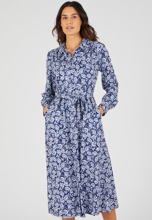 Abito floreale blu navy con collo a camicia, maniche lunghe e vita stretta. Dotato di due tasche laterali e di una gonna fluente.