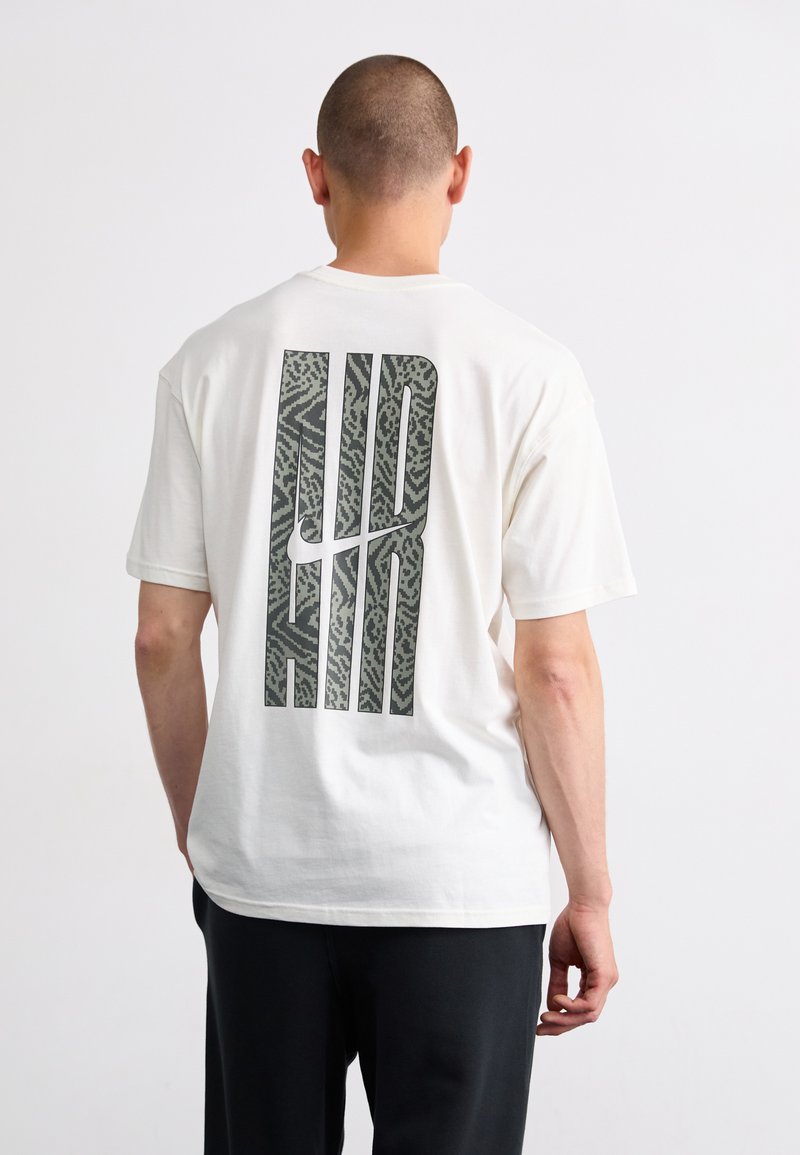 Hvid bomulds t-shirt med en stor, tekstureret grå "AIR" grafik på ryggen. Korte ærmer og en afslappet pasform.
