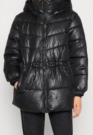 Czarna pikowana kurtka puchowa zapinana na zamek z przodu, z kapturem, elastycznymi mankietami i regulowanymi sznurkami w talii, noszona przez osobę z rękami w kieszeniach.