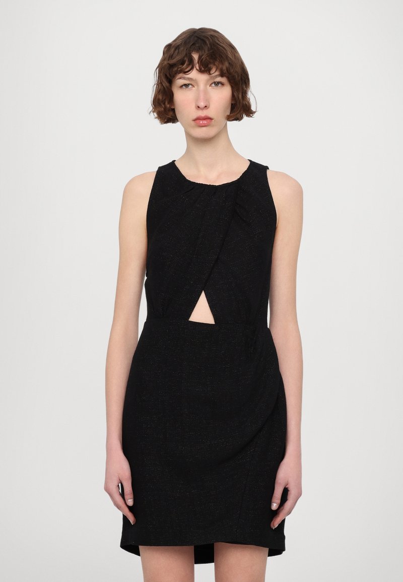 Vestido negro con una tela texturizada, diseño sin mangas, detalle de torsión en la parte delantera y un corte en la cintura. Largo por encima de la rodilla.