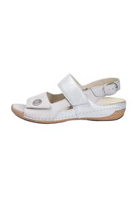 White leather sandal with a reflective silver strap, open toe, and adjustable ankle strap, featuring a circular accent near the toe.