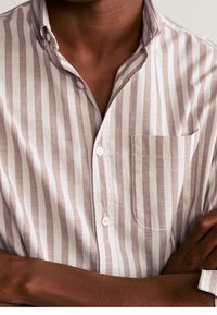 Camisa de botones con rayas verticales en tonos rosa claro y blanco, confeccionada en tela suave, con un bolsillo en el pecho y un diseño de cuello clásico.