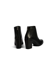 Bottines en cuir noir avec un bout arrondi, un talon carré de hauteur intermédiaire et une fermeture éclair sur le côté pour un enfilage facile. Texture lisse avec des accents minimalistes.