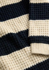 Maglione lavorato a maglia con strisce alternate di navy e crema, in un tessuto testurizzato e con polsini a coste, che mette in mostra un materiale caldo e morbido.