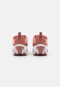 Sapatos de desporto em rosa, com materiais texturizados, logotipo em destaque, aba do calcanhar reforçada e sola de borracha branca com um design de tração pronunciado.